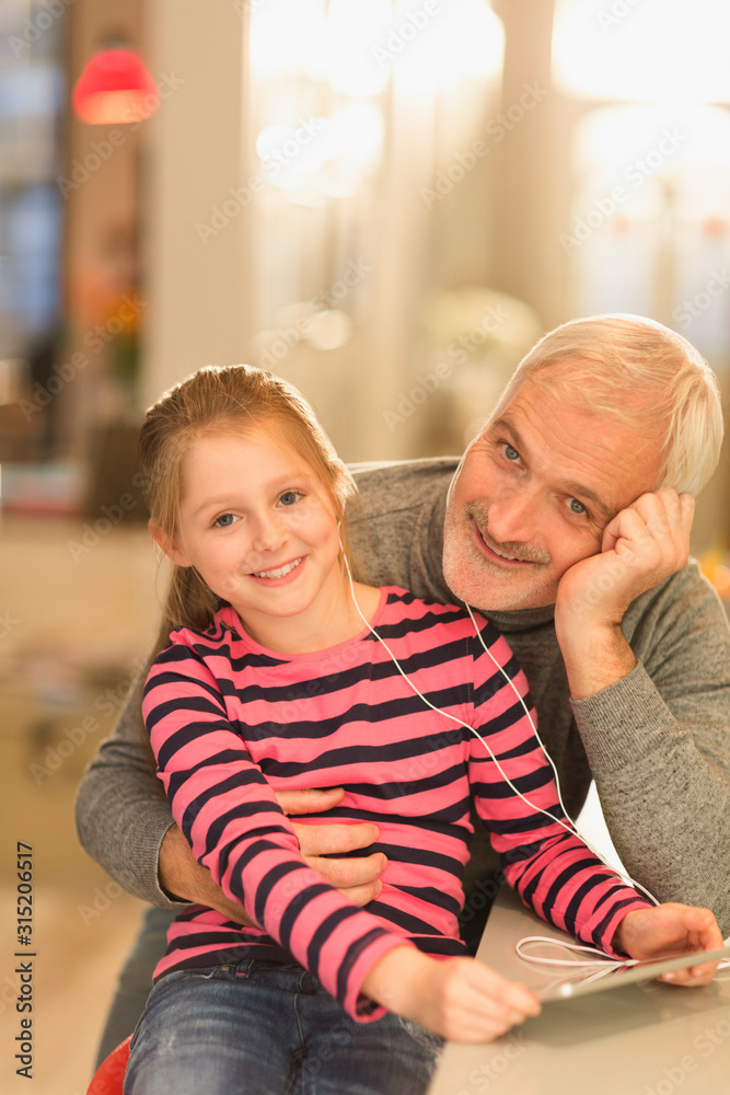 Portrait smiling father daughter bonding, sharing headphones using digital tablet Portrait smiling father daughter bonding, sharing headphones using digital tablet