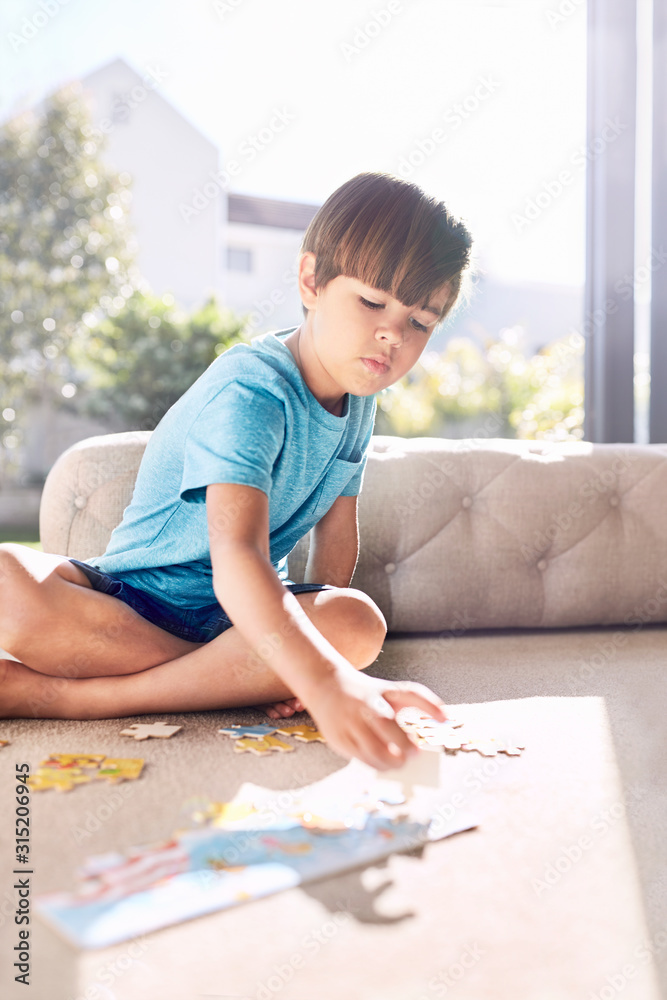 Focused boy assembling jigsaw puzzle on sofa Focused boy assembling jigsaw puzzle on sofa