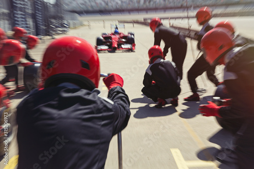 Pit crew ready for nearing formula one race car driver in pit lane