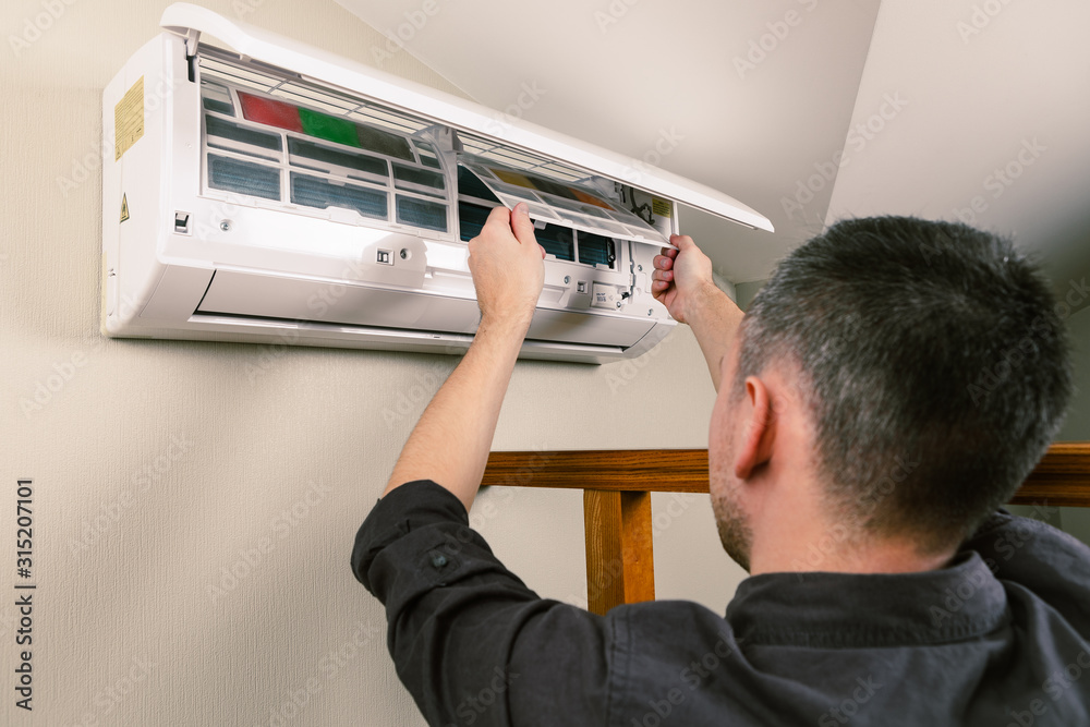 Obraz premium Male technician cleaning air conditioner indoors