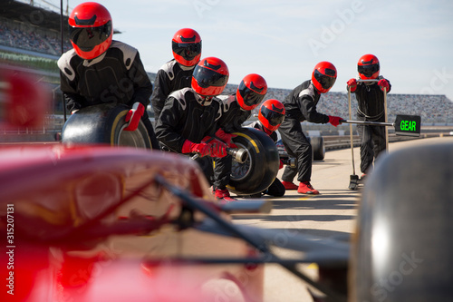 Pit crew with tires ready for nearing formula one race car in pit lane photo