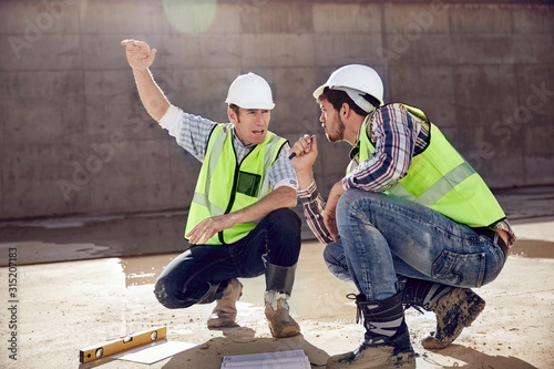 Construction worker and engineer talking at sunny construction site