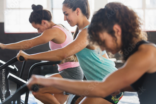 Focused young women using elliptical bikes in exercise class
