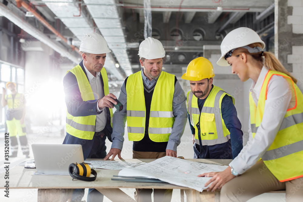 Engineers reviewing blueprints at construction site