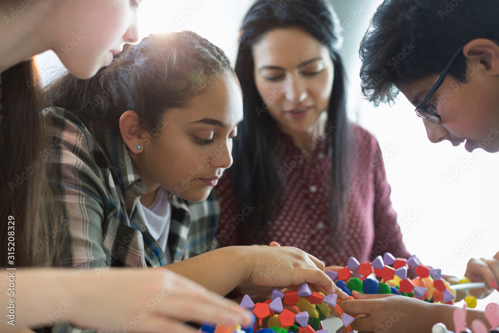 Curious students examining DNA model in classroom Curious students examining DNA model in classroom