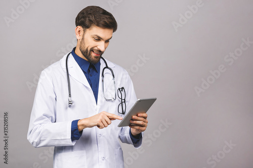 Smiling doctor using a tablet computer isolated on a grey background.