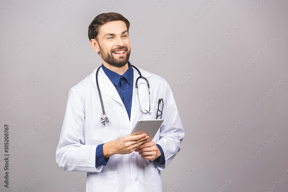Smiling doctor using a tablet computer isolated on a grey background.