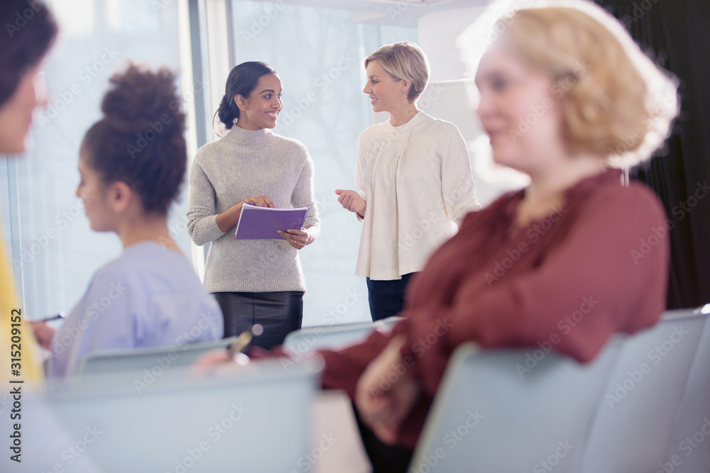 Businesswomen talking in conference audience Businesswomen talking in conference audience
