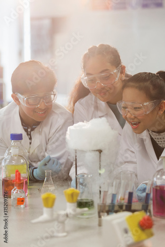 Surprised students conducting scientific experiment, watching chemical reaction in classroom laboratory