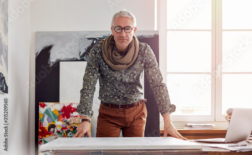 Portrait confident male photographer standing over canvas in art studio photo