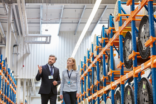 Businessman and businesswoman touring fiber optic factory floor