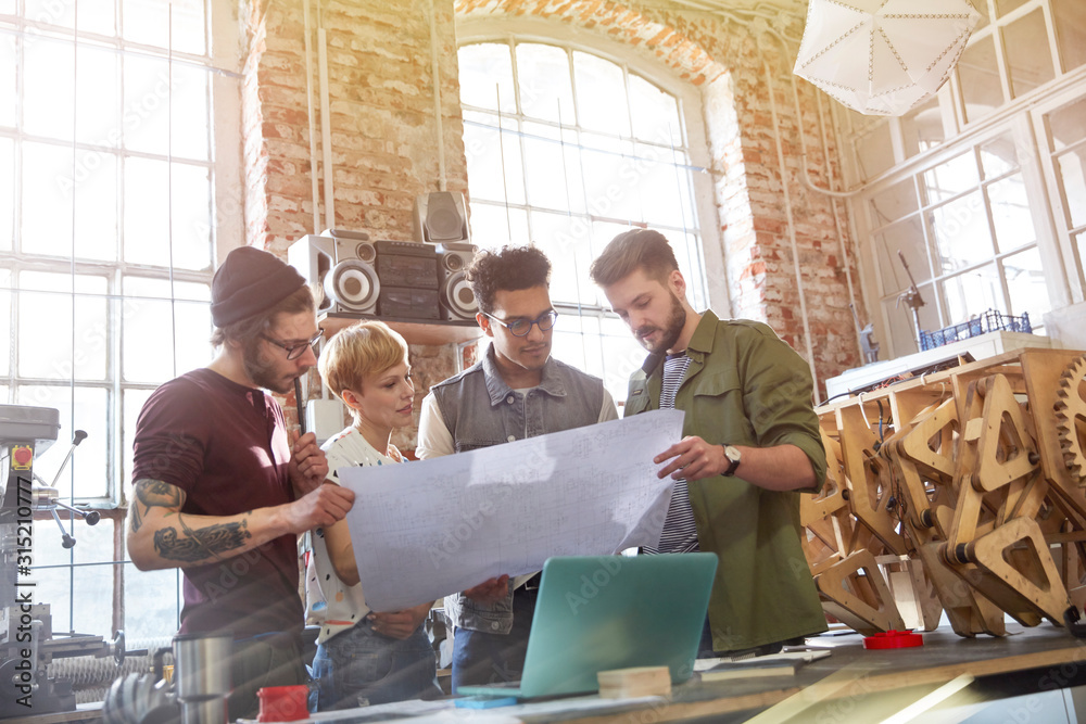 © Agnieszka Olek/Caia Image - Designers examining blueprints in workshop