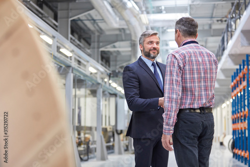 Business owner and supervisor handshaking in fiber optics factory