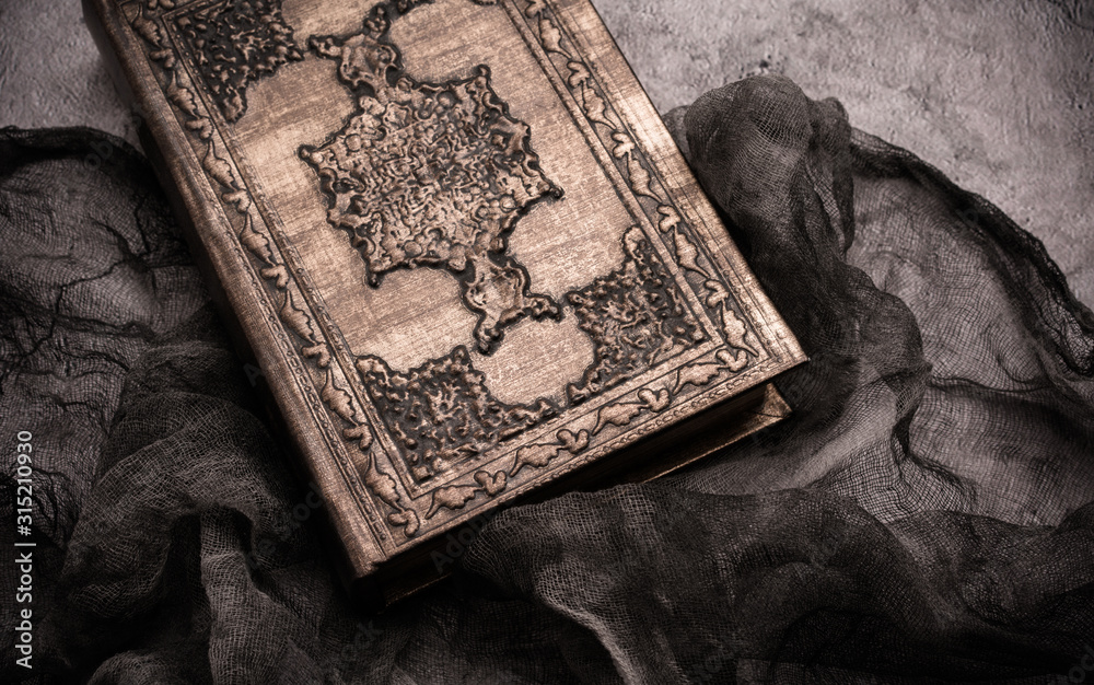 Naklejka premium Old book with spells and magic wand on gray background with witch rag. Copy space for text