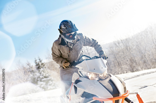 Man riding snowmobile in sunny snowy field photo