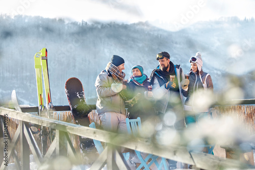 Skier friends talking drinking cocktails on sunny balcony apres-ski photo