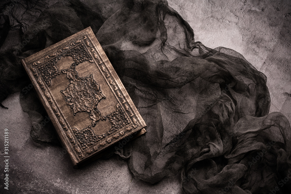 Obraz premium Old book with spells and magic wand on gray background with witch rag. Copy space for text