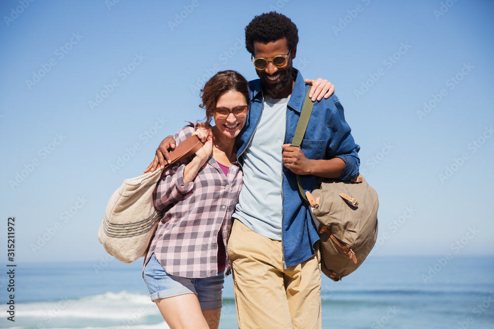 Smiling, affectionate multiethnic couple walking on sunny summer ocean beach Smiling, affectionate multiethnic couple walking on sunny summer ocean beach