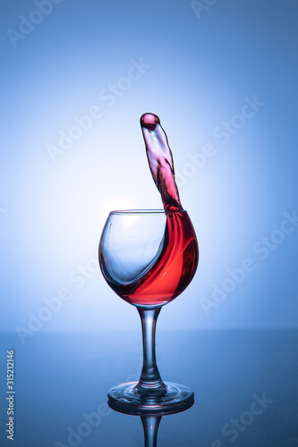 Splashing alcohol in a glass on a blue background