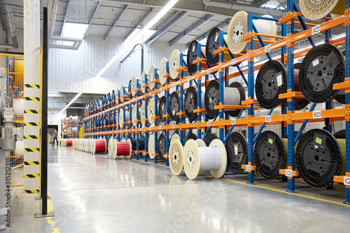 Large spools on racks in fiber optics factory