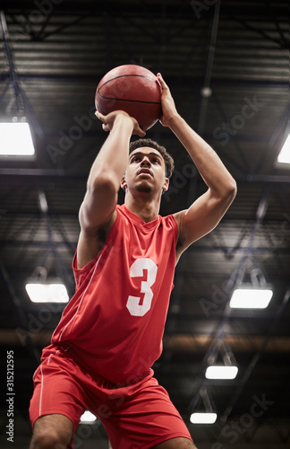 Focused young male basketball player shooting free throw