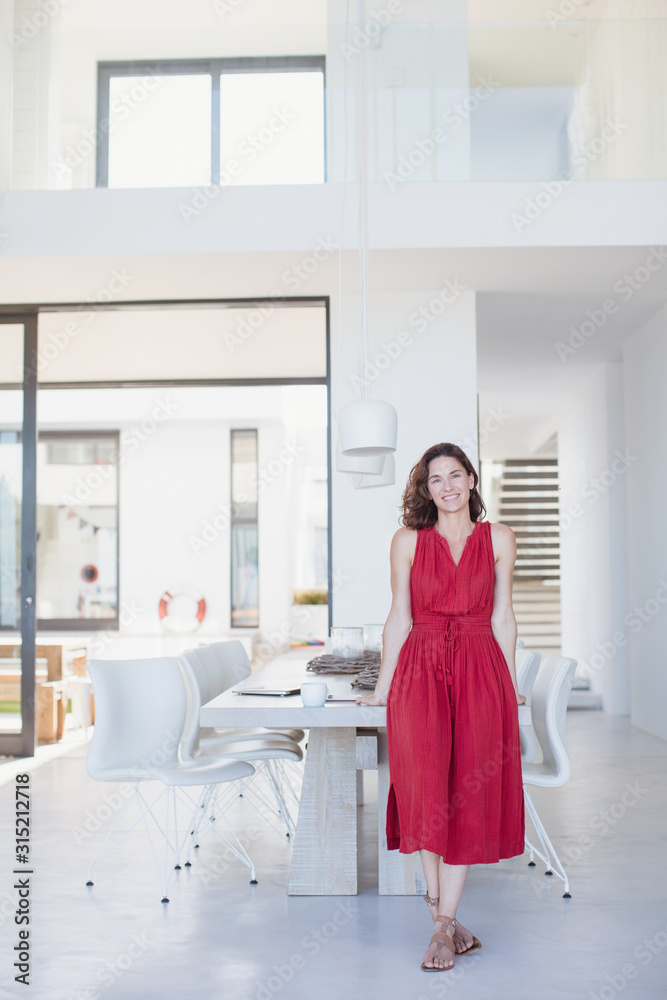 Portrait smiling brunette woman in red dress leaning on dining table Portrait smiling brunette woman in red dress leaning on dining table