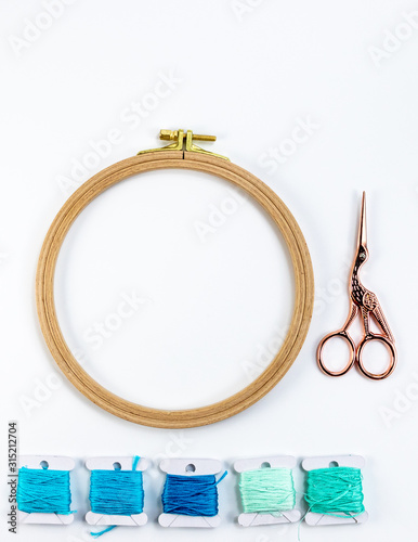 Embroidery accessories. Multicolored bundles of thread, scissors, sewing needles. White background ready for copywriting.