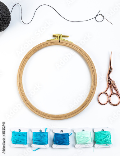 Embroidery accessories. Multicolored bundles of thread, scissors, sewing needles. White background ready for copywriting.