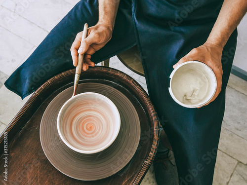 Fotobehang Ceramist at a pottery workshop Top view photo Man is glazing a ceramic plate at