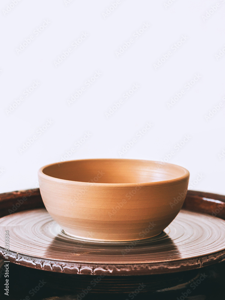 Fototapeta premium Ceramic plate Close up photo with copy space New craft ceramic plate is standing on a potter's wheel