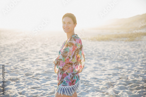 Portrait smiling, confident brunette woman in swimsuit coverup on sunny summer sunset beach photo