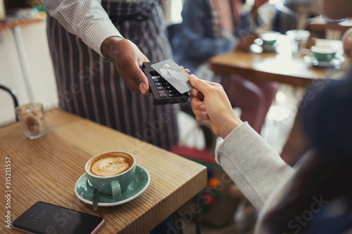 Customer credit card paying worker contactless payment in cafe