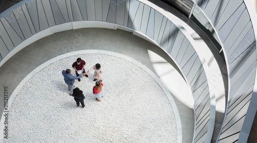 View from above business people handshaking in round modern office atrium courtyard photo