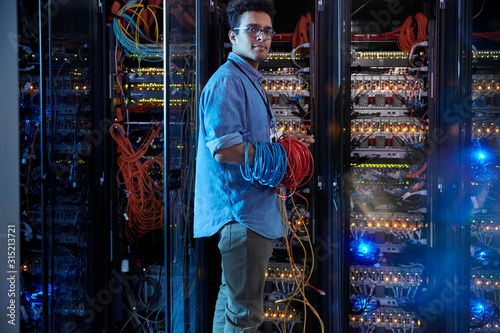 Portrait confident male IT technician holding cables in server room