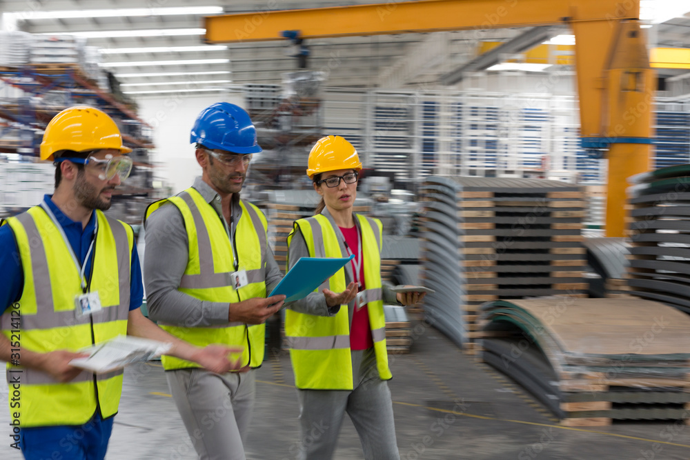 Supervisor and workers with clipboard and digital tablet walking in factory Supervisor and workers with clipboard and digital tablet walking in factory