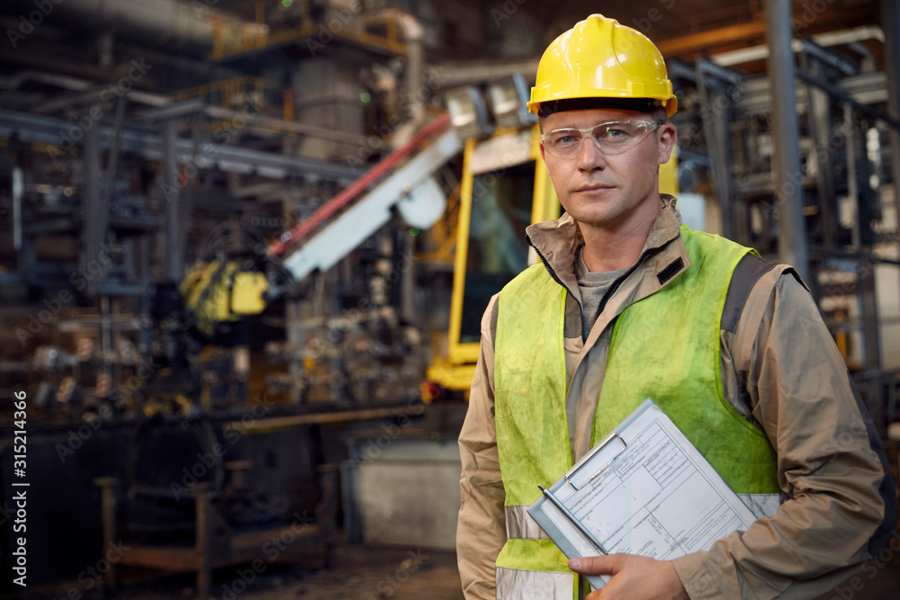 Portrait serious, confident steelworker with clipboard in steel mill
