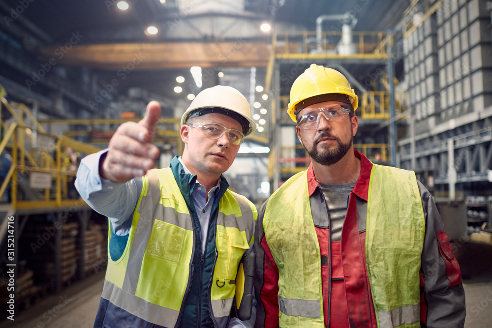 Steelworkers talking, gesturing in steel mill Steelworkers talking, gesturing in steel mill