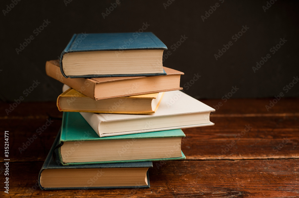stack of colored books on old wooden shelf with dark background