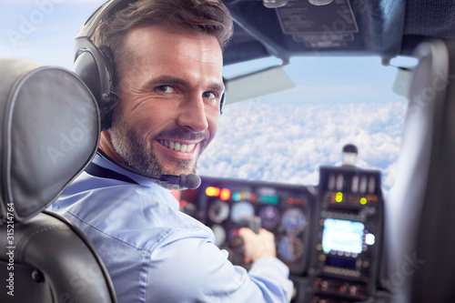 Portrait smiling, confident male pilot flying airplane in cockpit photo