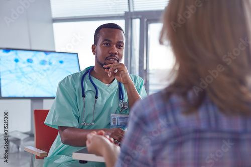 Male surgeon talking to female patient in hospital photo