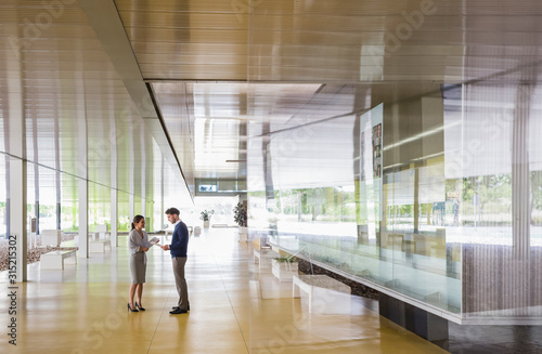 Businessman and businesswoman talking in modern office lobby corridor