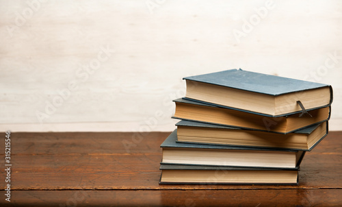 stack of blue books on old wooden shelf with dark background