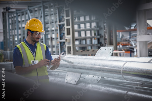 Male worker using digital tablet in steel factory photo