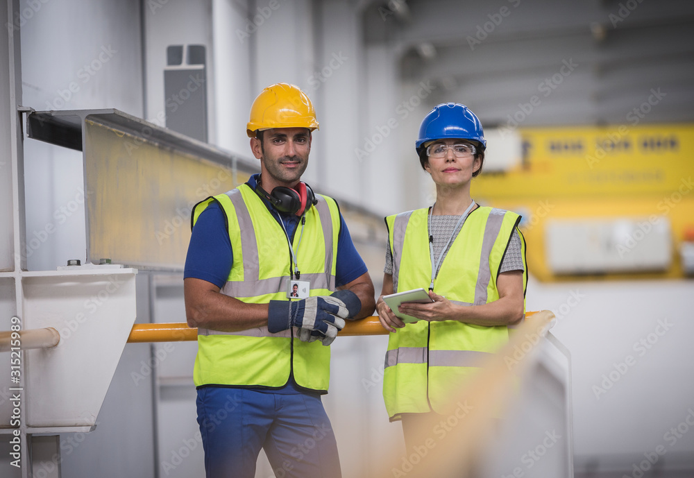 Portrait confident supervisors with digital tablet on platform in factory