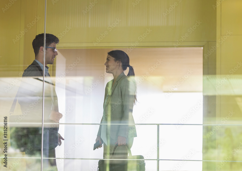 © Caiaimage/Martin Barraud/Caia Image - Businessman and businesswoman talking in modern office corridor