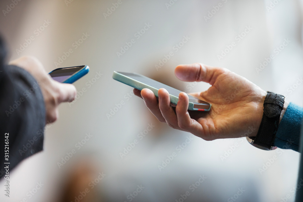 © Sam Edwards/Caia Image - Close up men holding smart phones