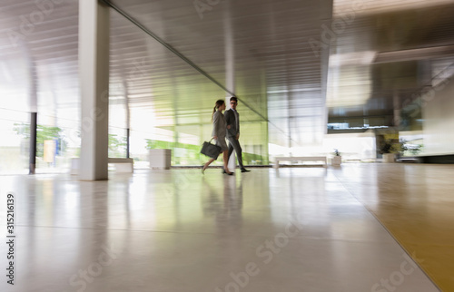 Business people walking in modern office corridor