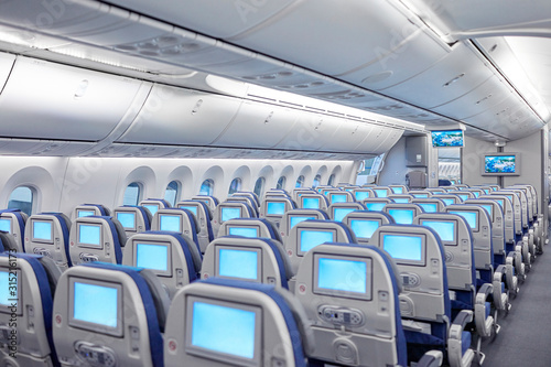 Rows of seats with entertainment screens on airplane photo