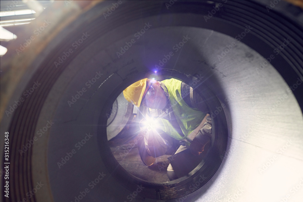 © Caiaimage/Agnieszka Olek/Caia Image - Steelworker with flashlight examining steel part in steel mill