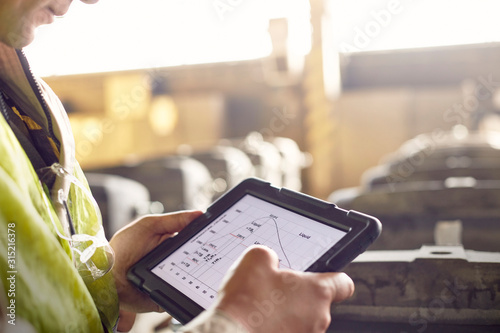 Close up steelworker reviewing digital graph on digital tablet in steel mill photo